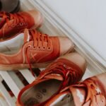 Rusty red sneakers organized neatly on a sleek white shoe rack indoors.