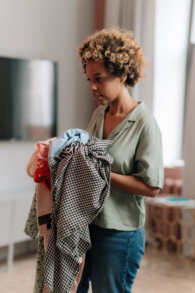 Femme concentrée triant et tenant un paquet de vêtements à la maison, éclairage naturel.