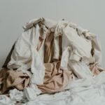 Un tas de vêtements beiges et blancs empilés négligemment sur un plancher en bois.